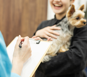 カウンセリングシートに記入するトレーナーと抱っこされた犬